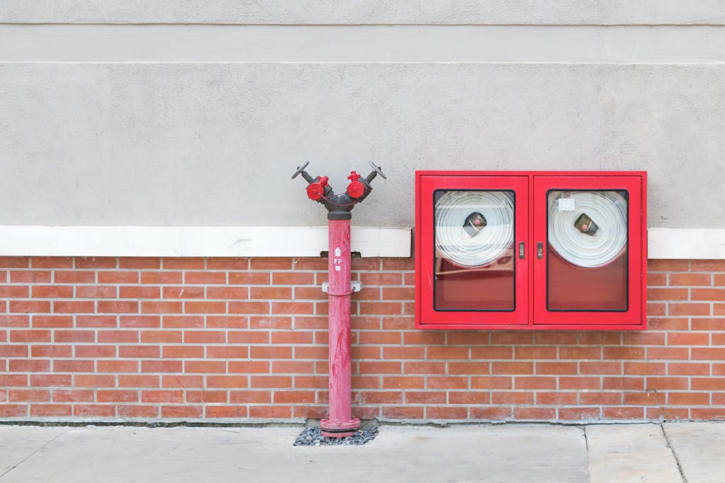 Outdoor fire hydrant and hoses against a brick wall, emphasizing fire safety.